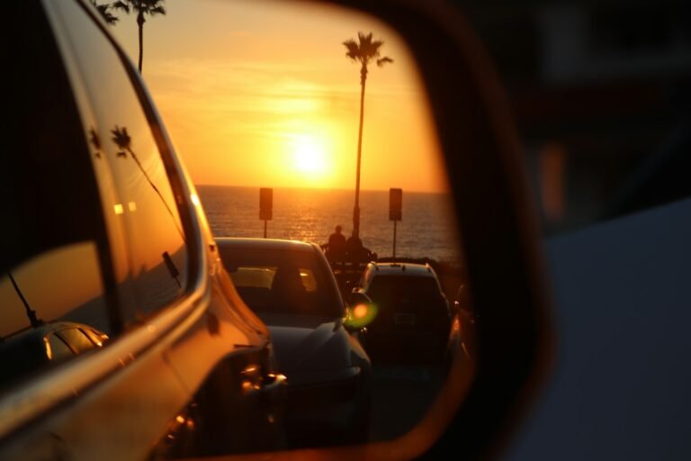 Car mirror and side window at sunset on the California coast, illustrating legal tint in California